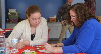 Two women sitting at a table, looking at a paper.