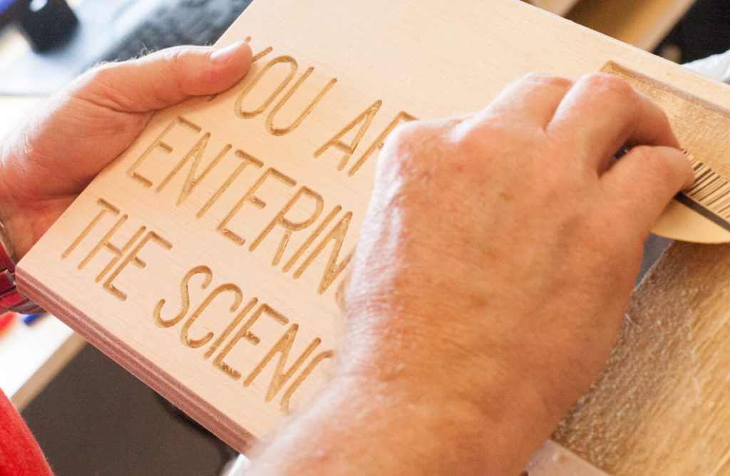 A sign with etched letters on a block of wood