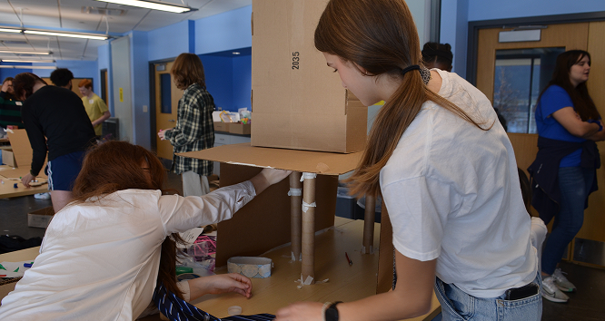 Two teenagers girls are putting the finishing touches on their science experiment.
