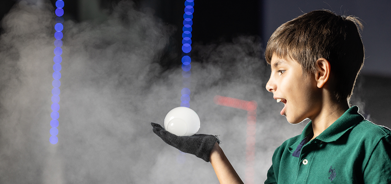 A boy looking at a bubble he's holding in his hand.