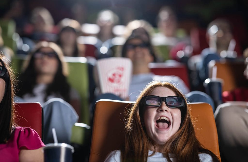A young girl with 3D glasses is watching a film.