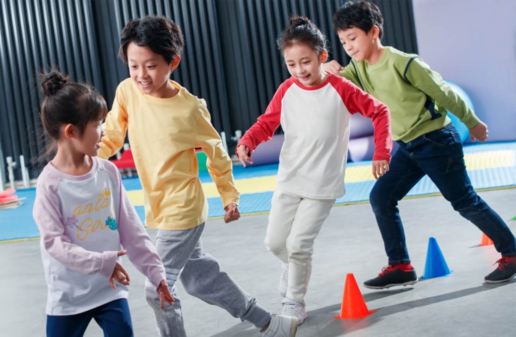 Children running around orange and blue cones